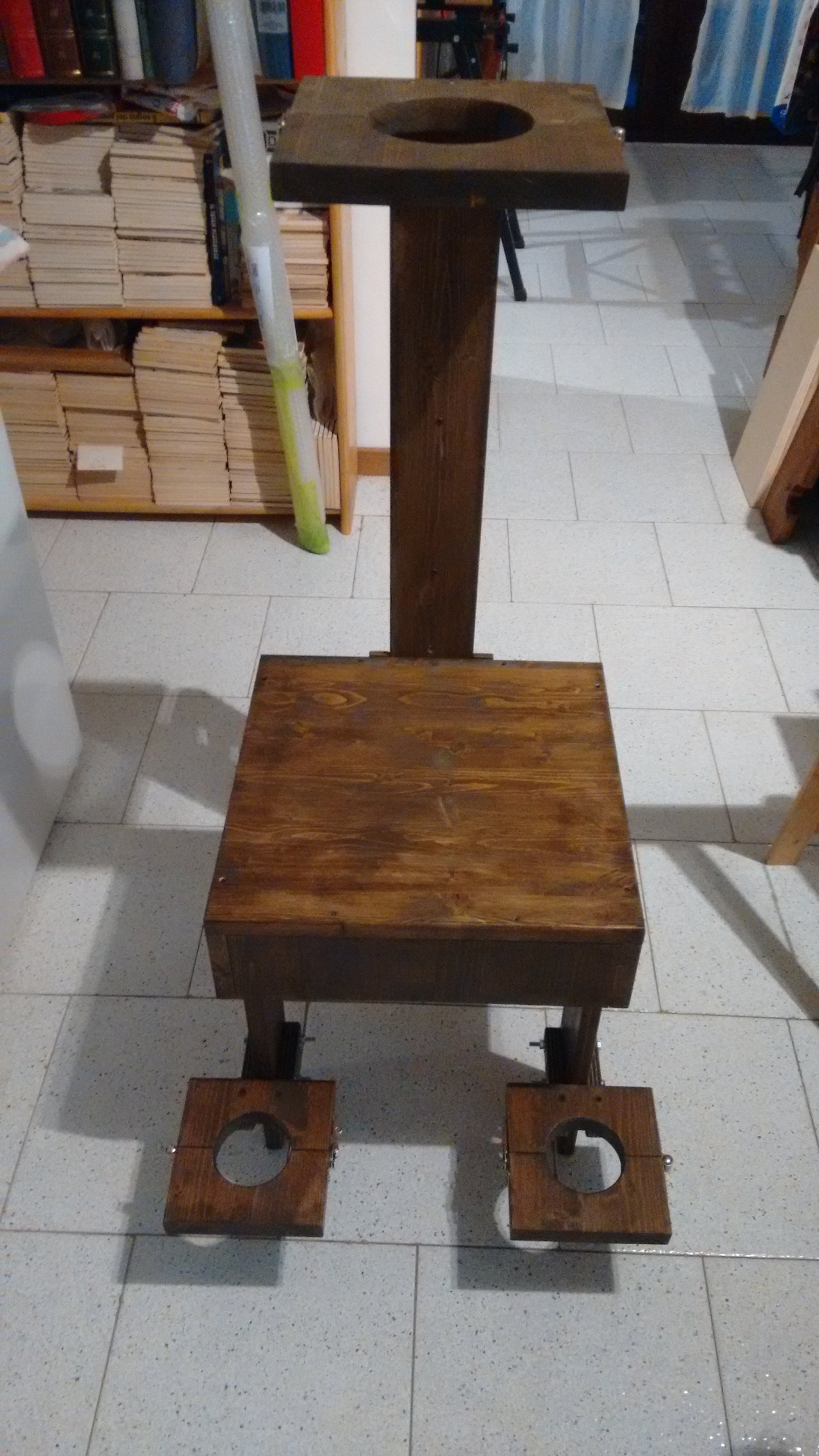 Walnut-stained wooden interrogation chair with bondage restraints.