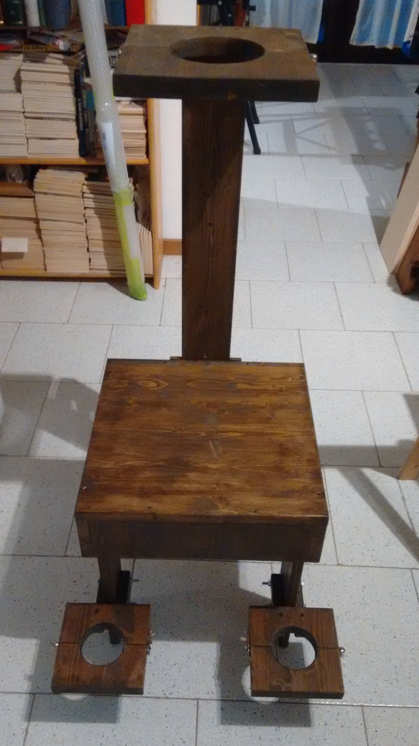 Walnut-stained wooden interrogation chair with bondage restraints.
