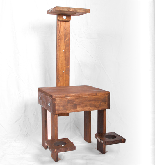 Wooden BDSM interrogation chair with wrist, ankle, and neck stocks.